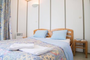Una cama bien hecha con una colcha estampada, dos almohadas y una toalla doblada sobre la cama.