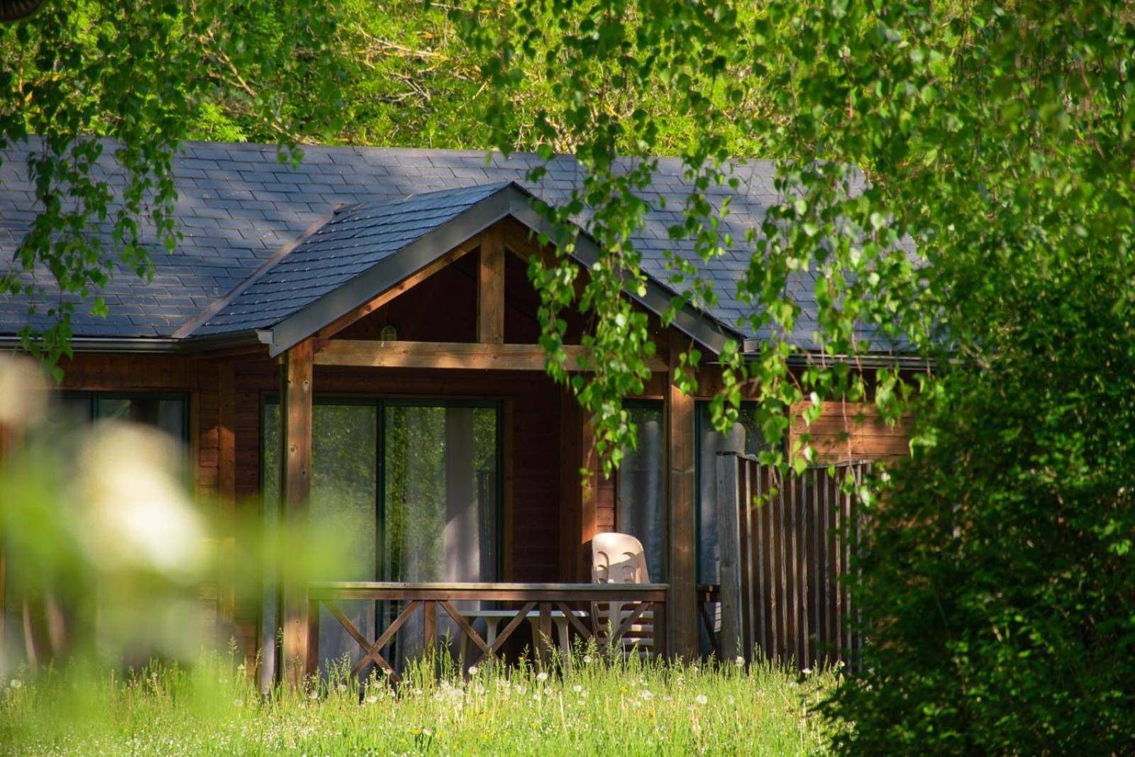 A wooden cabin with a porch, surrounded by greenery.