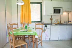 Una cocina compacta con comedor, que incluye una mesa con sillas, microondas, cafetera y pileta.