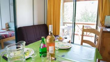 Un coin repas avec une table dressée pour deux personnes, agrémenté d’une bouteille de vin, d’une carafe et d’assiettes.