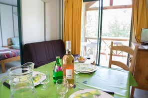 Un coin repas avec une table dressée pour deux personnes, agrémenté d’une bouteille de vin, d’une carafe et d’assiettes.