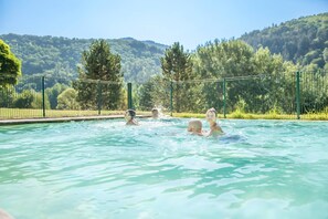 A swimming pool with clear water, surrounded by a fence and trees.