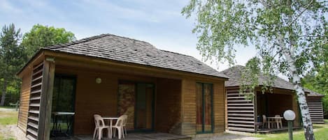 Une cabane en bois avec une véranda, une table et des chaises.