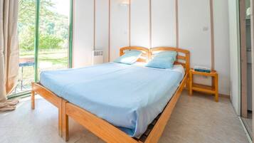 A bedroom with a wooden bed, a nightstand, and a window with curtains.