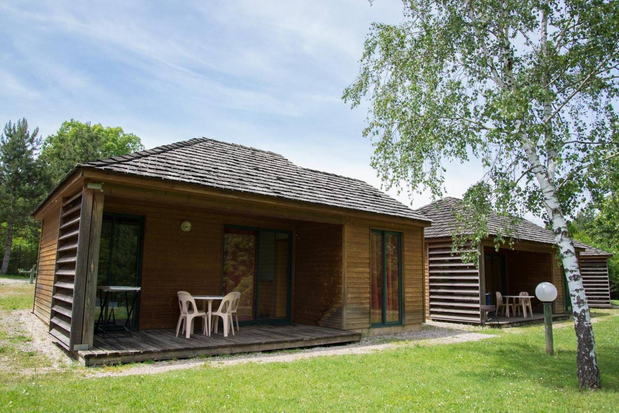 Une cabane en bois avec une véranda, une table et des chaises.