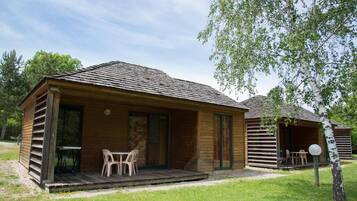 Une cabane en bois avec une véranda, une table et des chaises.
