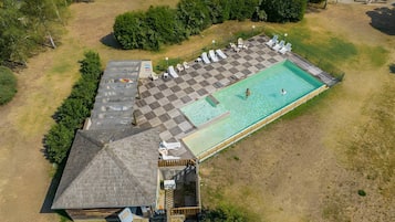 Luchtbeeld van een pand met een zwembad, een overdekt terras en een klein gebouw.