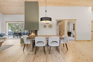 Een moderne eetruimte met een houten tafel en stoelen, een hanglamp en uitzicht op de omgeving.