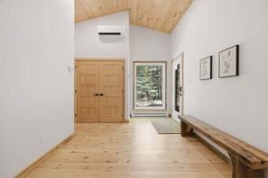 A hallway with wooden flooring, a bench, a door, and a framed botanical illustration on the wall. - Spa & Nature Escape | L'Ame des Bois (Grenville-sur-la-Rouge)