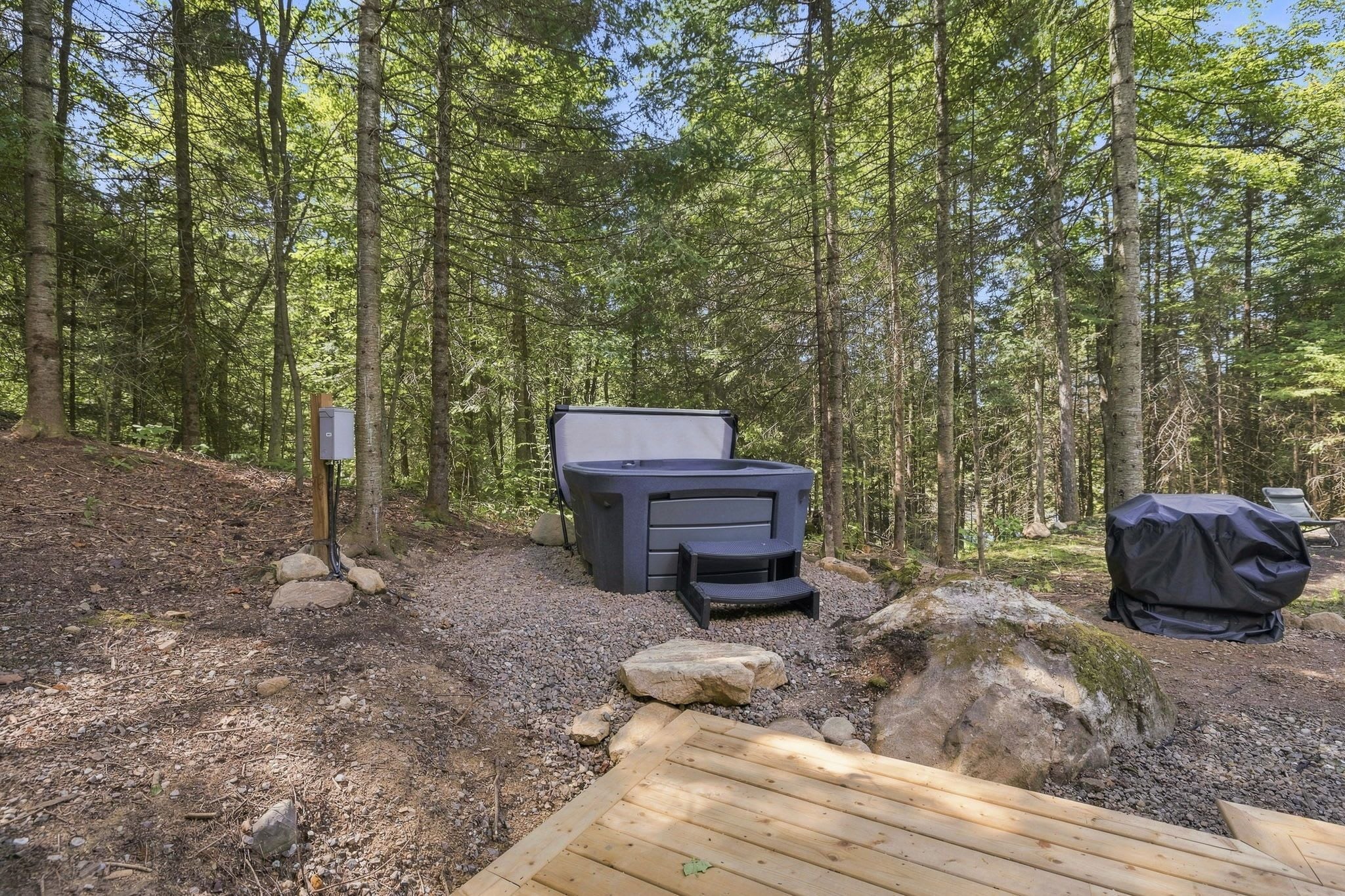 A campsite with a portable heater, a grill, and a picnic table surrounded by trees.