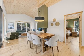 A modern interior with a wooden dining table, white chairs, and a large pendant light. - Spa & Nature Escape | L'Ame des Bois (Grenville-sur-la-Rouge)