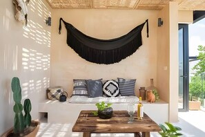 A room with a hammock, a white sofa, and a wooden table with plants. - Boho Style Penthouse With Private Pool 150 Wifi (Tulum)