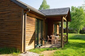 Une cabane en bois avec une véranda, une table et des chaises.