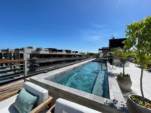 A rooftop pool with a clear view of the city skyline, surrounded by modern architecture and outdoor seating. - Xalet 307a Tulum Cenote y Beach Club Privileges (Tulum)