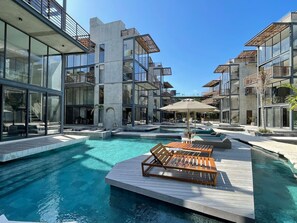 A modern hotel with a central swimming pool, outdoor seating, and a clear blue sky. - Xalet 307a Tulum Cenote y Beach Club Privileges (Tulum)