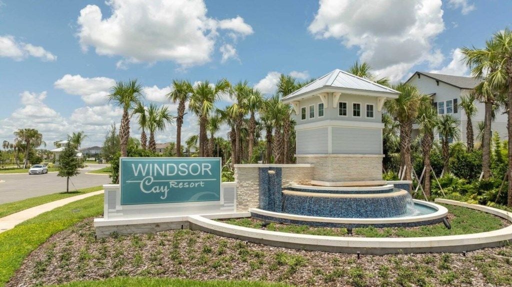 A sign for Windsor Cay Resort with a water feature and palm trees.