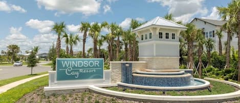 A sign for Windsor Cay Resort with a water feature and palm trees.