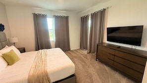 A hotel room with a bed, a television, a dresser, and curtains. - Champions Gate Condo 3 BD/ 2 BA - 1115 CD (Davenport)