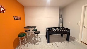 A room with a foosball table, a bar stool, and a sign on the wall. - Champions Gate Condo 3 BD/ 2 BA - 1115 CD (Davenport)