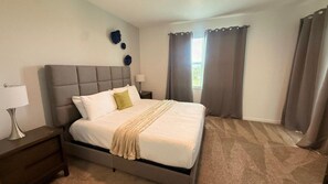 A bedroom with a bed, nightstand, lamp, and curtains. - Champions Gate Condo 3 BD/ 2 BA - 1115 CD (Davenport)