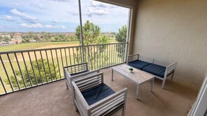 A balcony with a view of a residential area, a small table, and two chairs. - Champions Gate Condo 3 BD/ 2 BA - 1115 CD (Davenport)