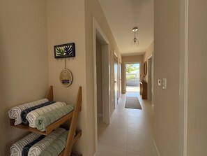 A hallway with a bench, a wall-mounted towel rack, and a door leading to a room. - Three Harbour Villa in Samaan Grove (Canaan, Tobago)