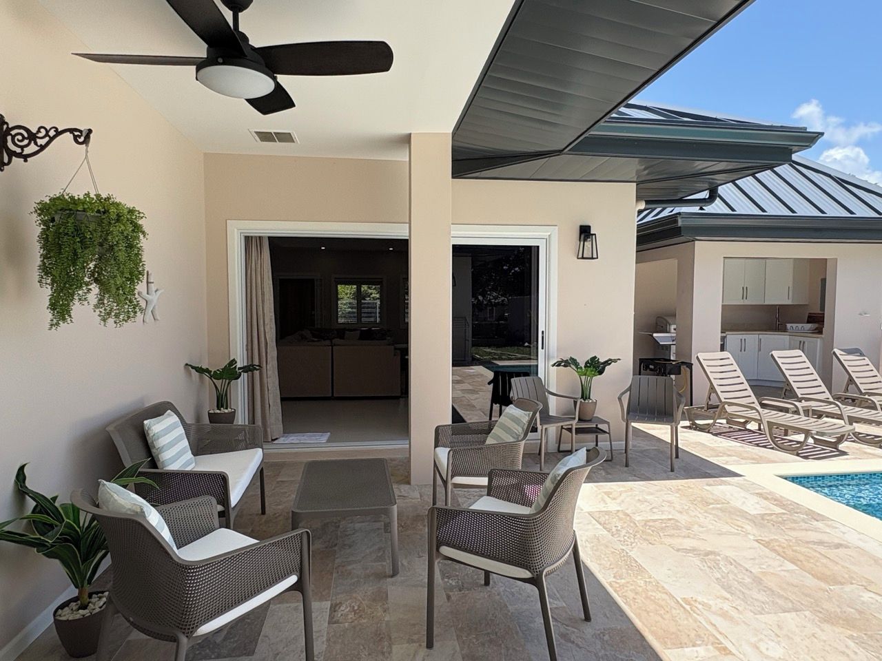 An outdoor patio with seating, a ceiling fan, and a pool.