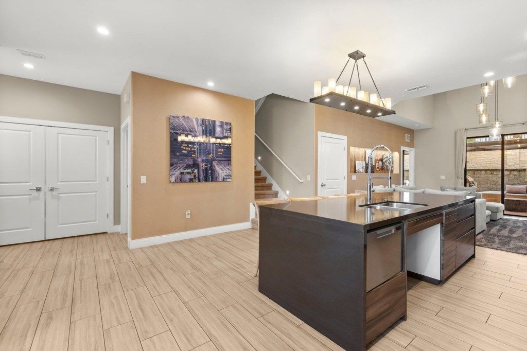 A modern kitchen with a central island, built-in appliances, and a staircase leading to an upper level.