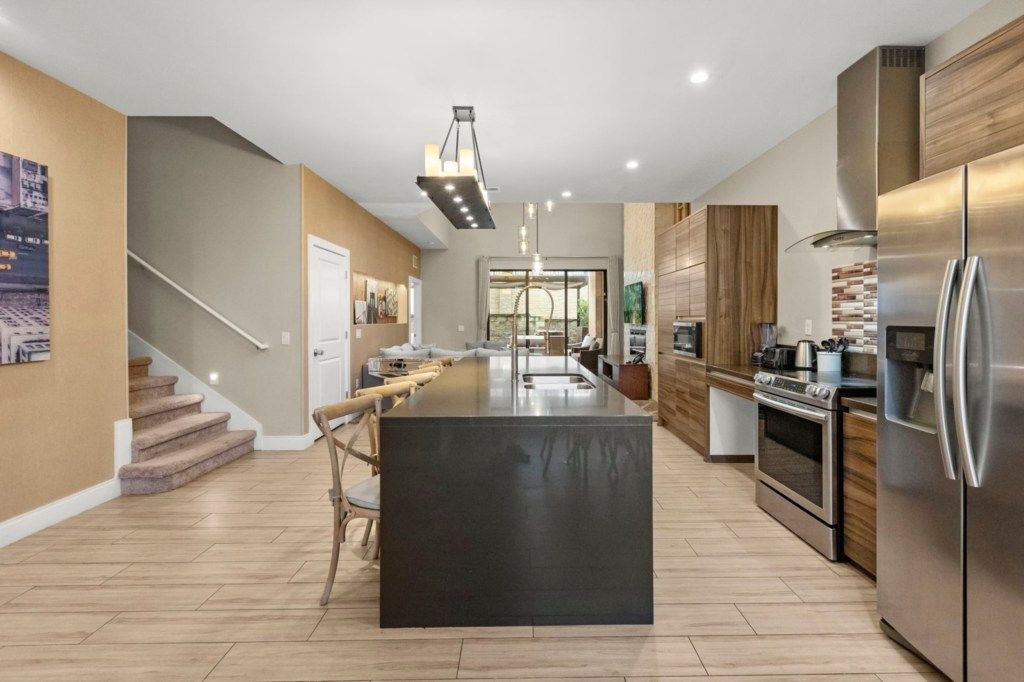 A modern kitchen with a central island, stainless steel appliances, and a staircase leading to another level.