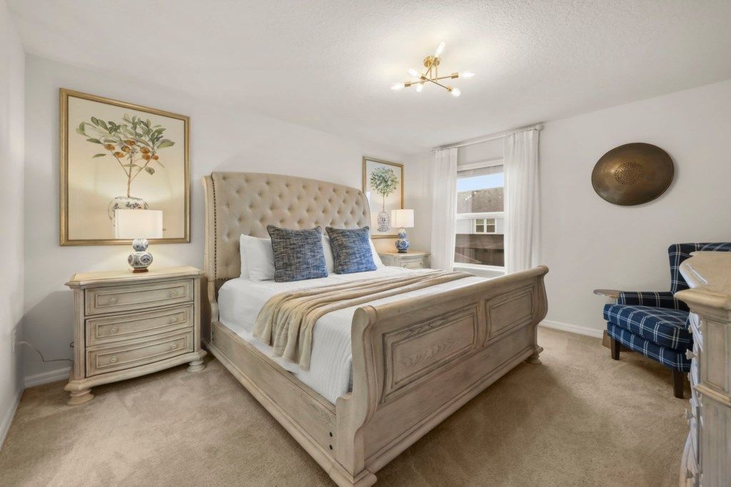 A bedroom with a large bed, two bedside tables, a window, and a decorative wall plate.