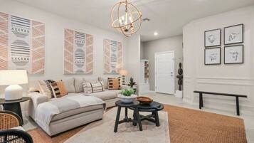 A modern living room with a sectional sofa, a round coffee table, and a chandelier.