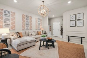A modern living room with a sectional sofa, a round coffee table, and a chandelier. - Halloween Game Room! Sleeps 10 Windsor Cay - 1273 ER (Clermont)