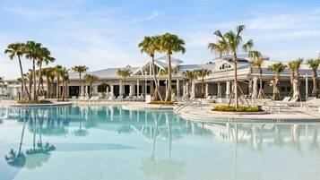 A resort with a large pool, palm trees, and lounge chairs.