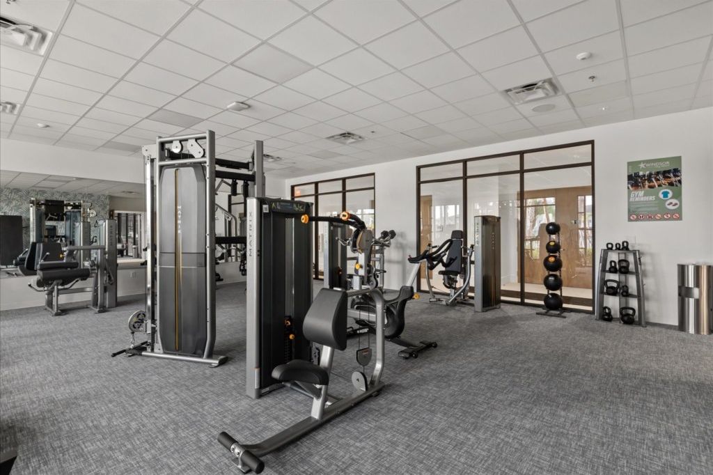 A gym with various exercise machines, a kettlebell rack, and a poster on the wall.