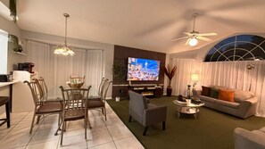 Ein Wohnzimmer mit Fernseher, einer Couch und einem Essbereich.