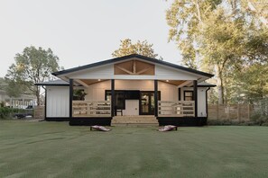 A two-story house with a covered porch, a front door, and a small front yard.