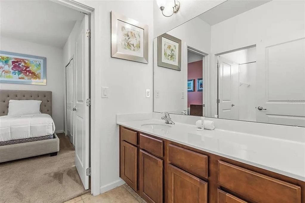 A bedroom with a bed, a large mirror, and a door leading to another room.