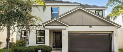 A two-story house with a garage, a front door, and a driveway.