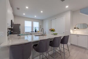 A modern kitchen with a central island, bar stools, and a large window. - 6 BD/ 6.5 BA/ Encore Resort at Reunion (404 SS) (Kissimmee)