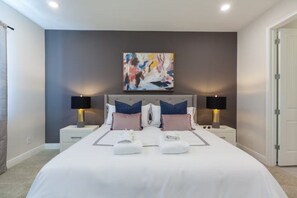 Un dormitorio moderno con una cama grande, dos mesitas de noche y un cuadro abstracto colgado en la pared.