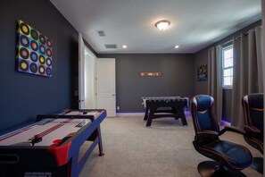 Una habitación con mesa de futbolín, mesa de billar y dardos.