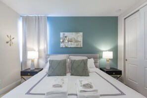 A hotel room with a bed, two bedside tables, a painting on the wall, and a door. - 6 BD/ 6.5 BA/ Encore Resort at Reunion (404 SS) (Kissimmee)