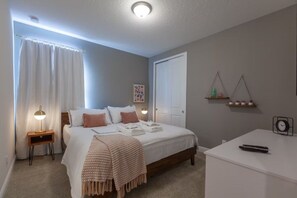 A bedroom with a bed, bedside table, lamp, and a desk with a clock. - 6 BD/ 6.5 BA/ Encore Resort at Reunion (404 SS) (Kissimmee)