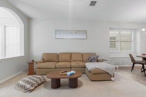 A living room with a beige sofa, a coffee table, a rug, and a painting on the wall.