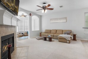 A living room with a fireplace, a sofa, a coffee table, and a ceiling fan. - Family-Friendly Frisco Home Near Universal & PGA (Frisco)