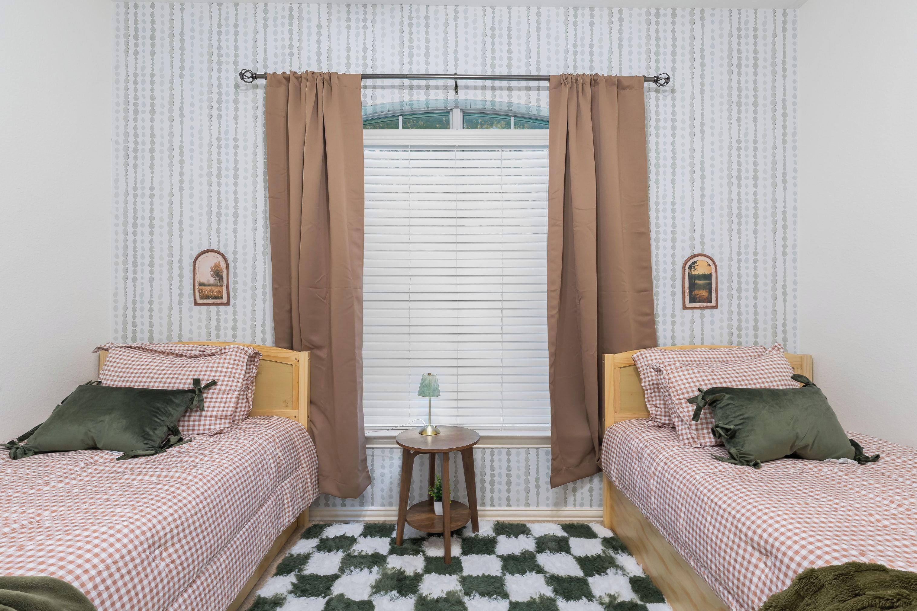 A room with two beds, a small table, and a window with curtains.