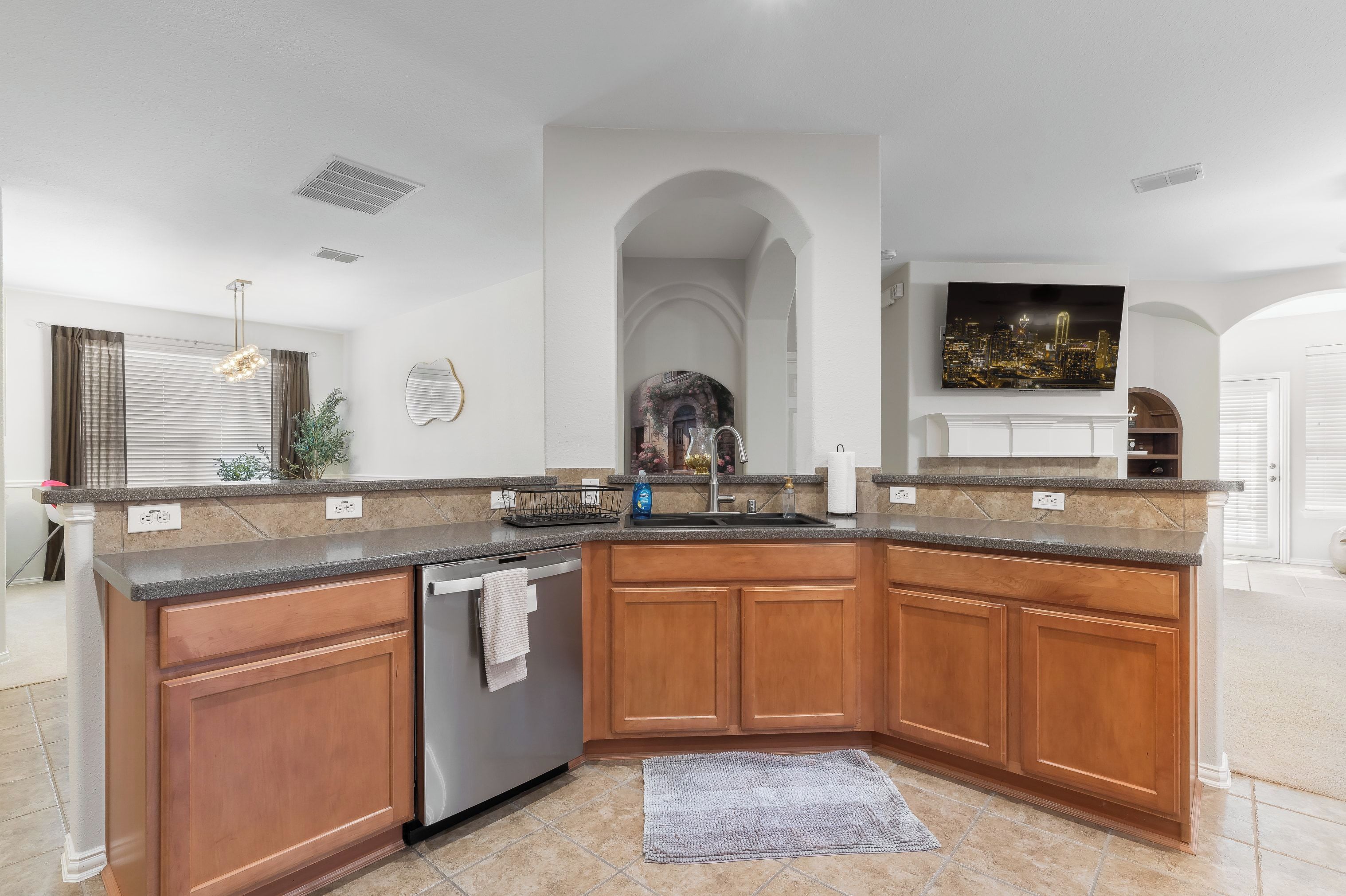 A modern kitchen with wooden cabinets, a stainless steel dishwasher, and a granite countertop.