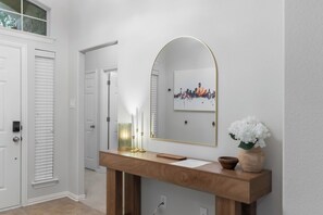 A hallway with a wooden console table, a mirror, and a cityscape artwork. - Family-Friendly Frisco Home Near Universal & PGA (Frisco)