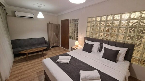 A hotel room with a bed, a sofa, a wardrobe, and a wall with a patterned design.