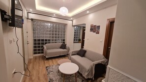 A cozy living room with two sofas, a small round table, and a large window with a view. - Cozy 1BR Located Near the UNESCO World Heritage Green Masjid in Bursa City (Yıldırım)